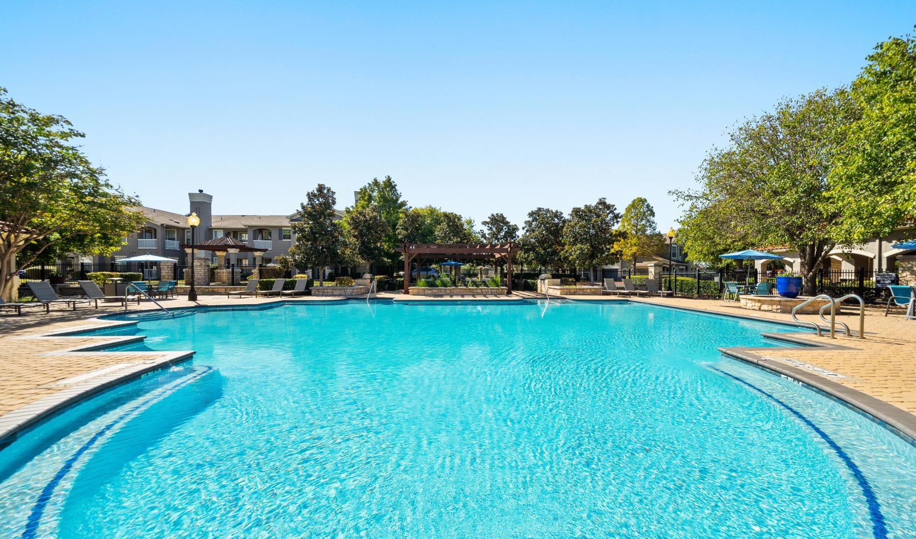 a swimming pool with trees and buildings in the background