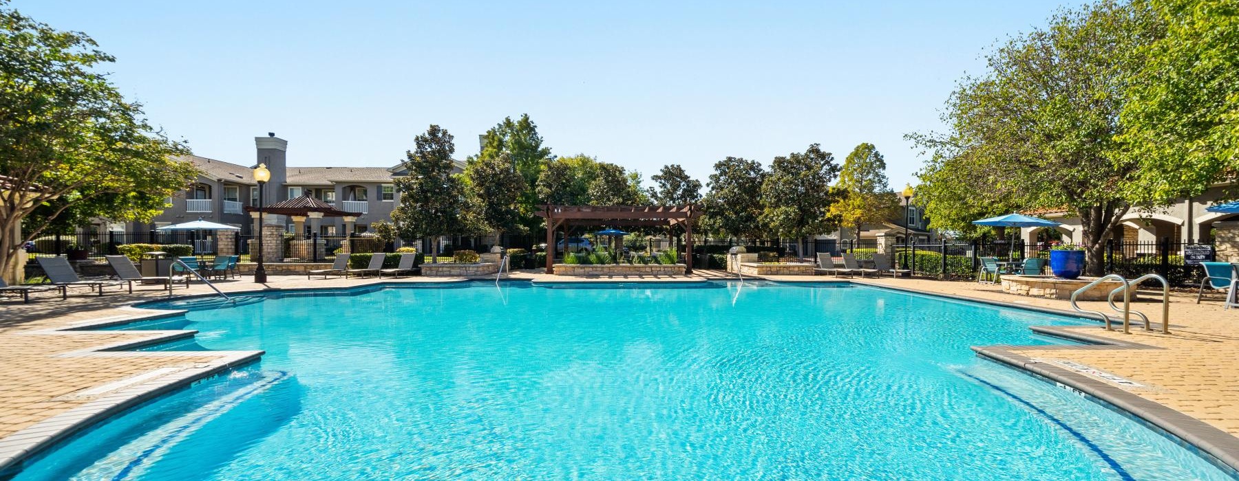 a swimming pool with trees and buildings in the background